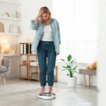 functional medicine for weight loss woman frustrated standing on scale at Apostol Integrative and Functional Medicine