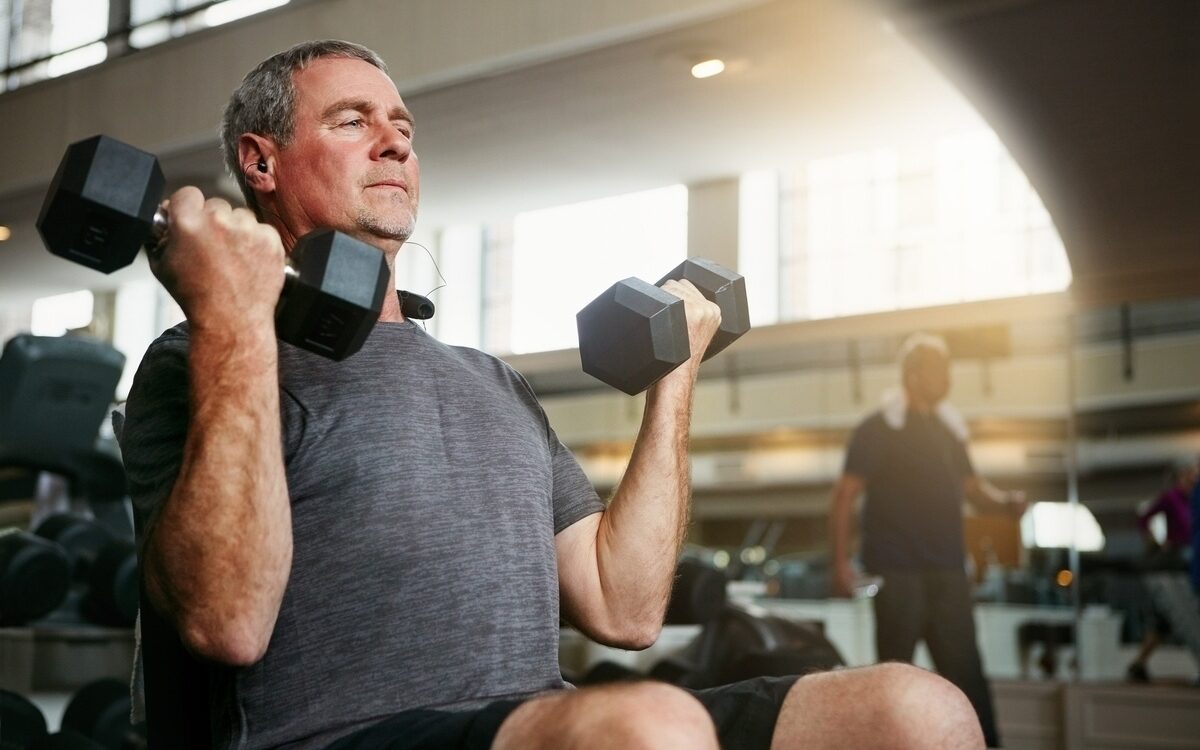 TRT and body composition shown by mature man lifting dumbbells during strength training at Apostol Integrative and Functional Medicine